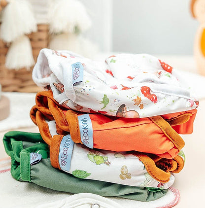 Stack of colorful baby diapers on a white surface with toys in the background
