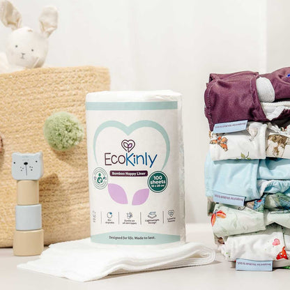 Stack of diapers with a container labeled 'Ecokinly' on a white surface with toys in the background.