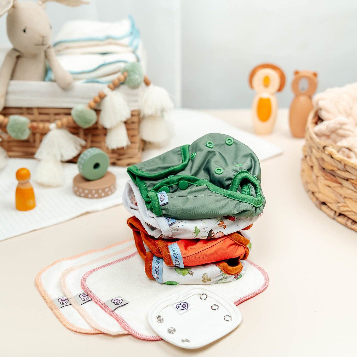 Stack of baby clothes with toys and a basket in a nursery setting